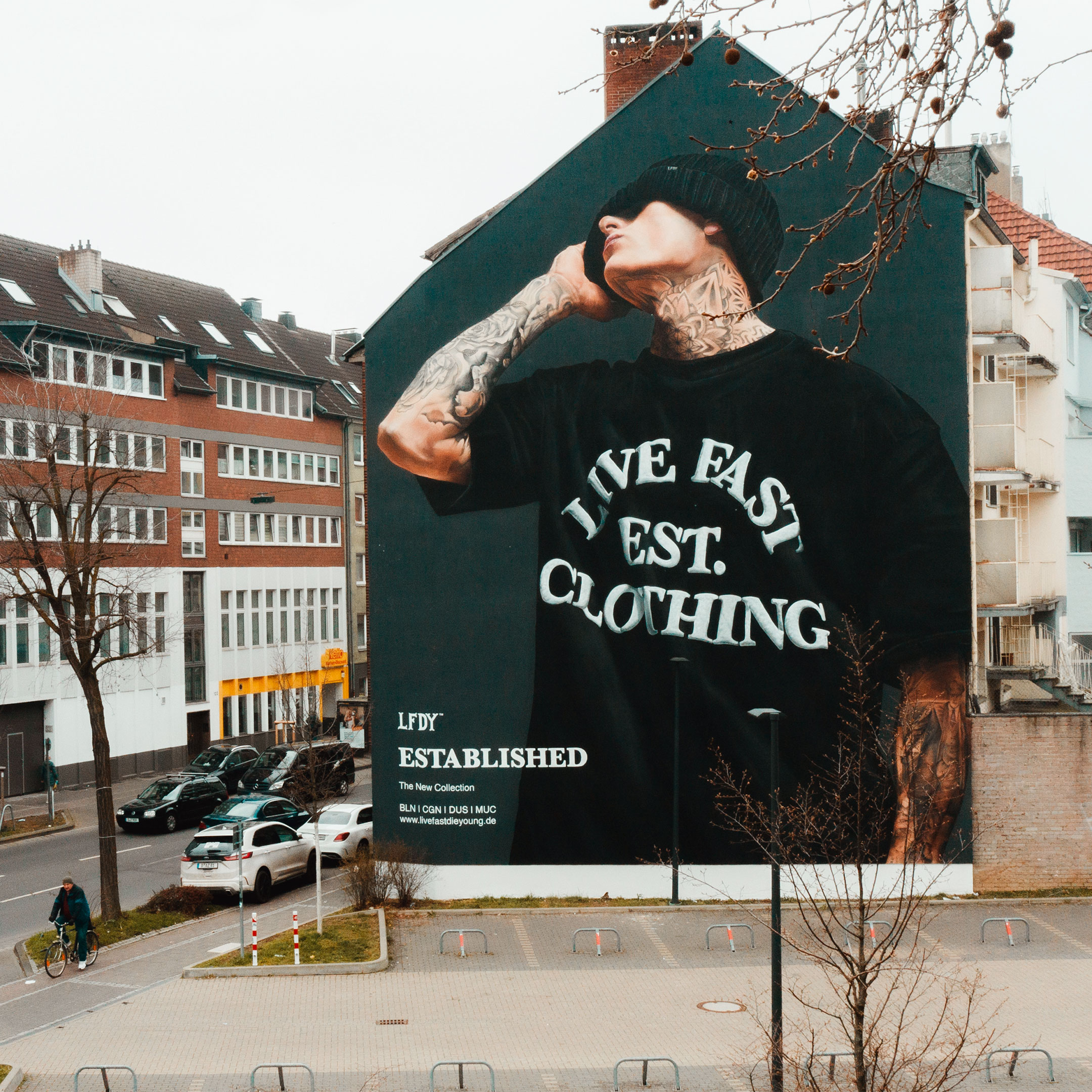 Zu sehen ist eine riesige Hauswand, die fotorealistisch mit einem großen Porträt besprüht wurde.