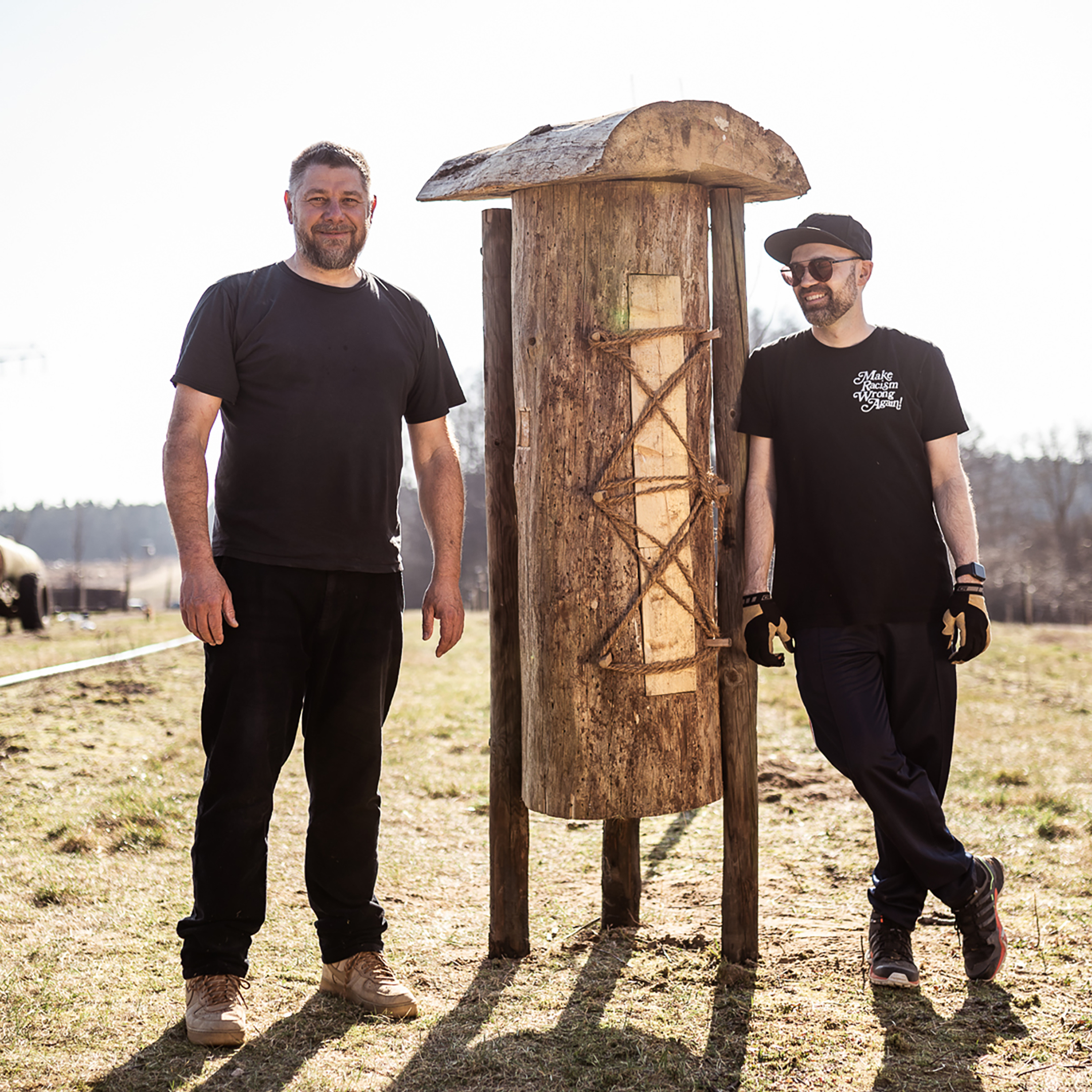 Die Gründer von Hoodlewood stehen vor einem Bienenhotel